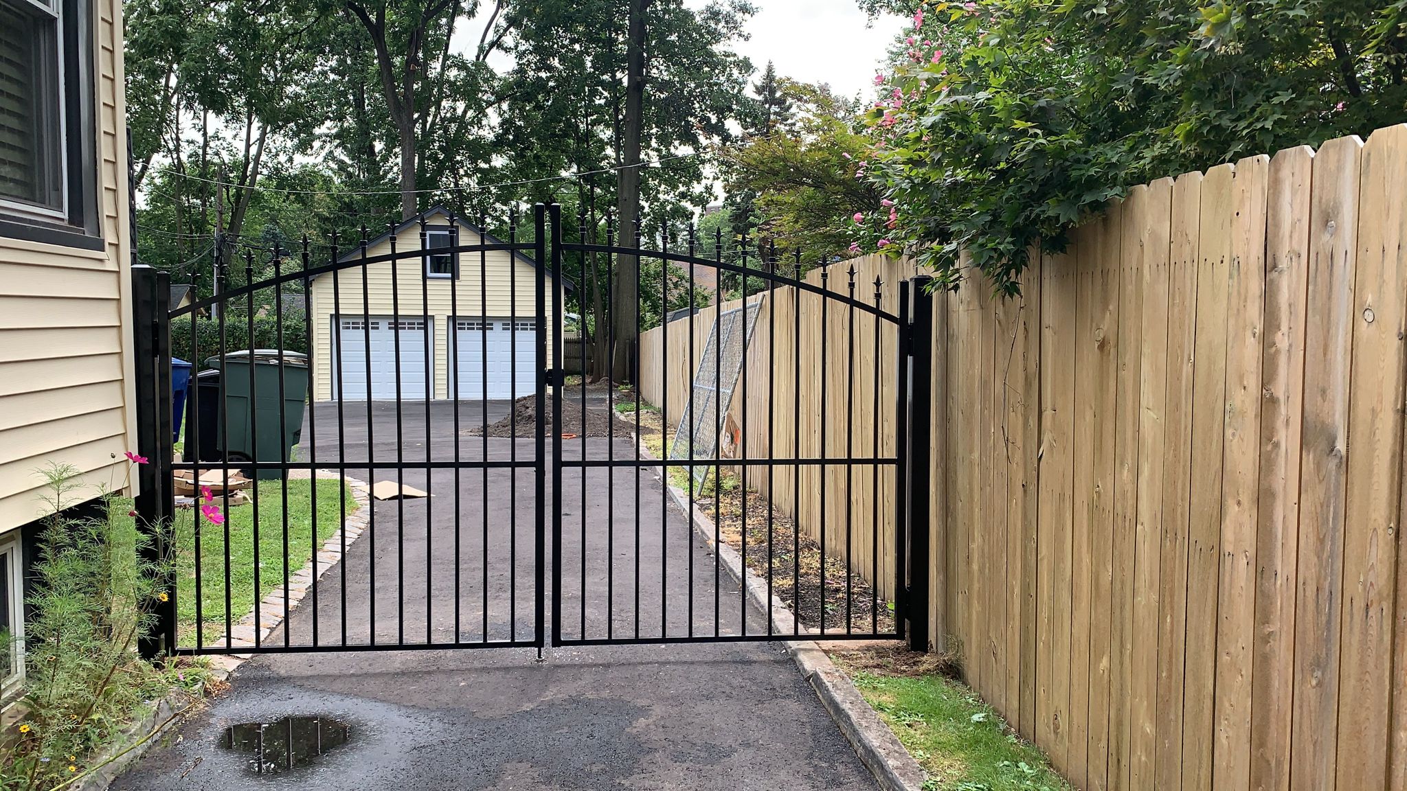 Arched ornamental gate set between wood privacy fence panels