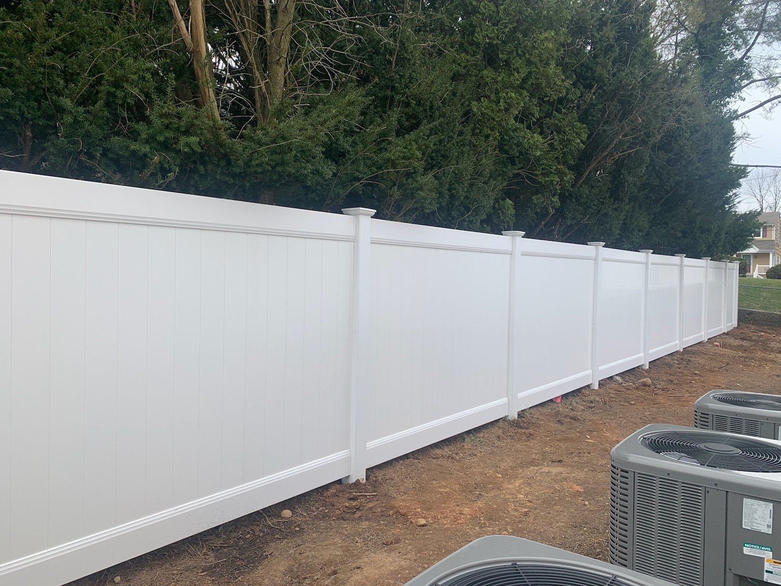 White PVC vinyl privacy fence panels installed along a property line
