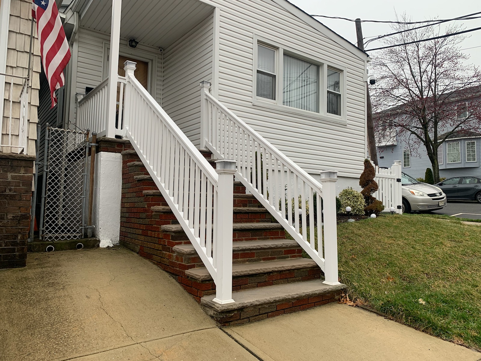 White vinyl porch railing installed along brick front steps